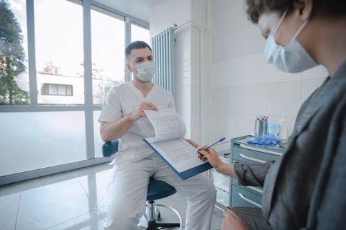 A healthcare professional discussing a document with a patient in a bright clinic